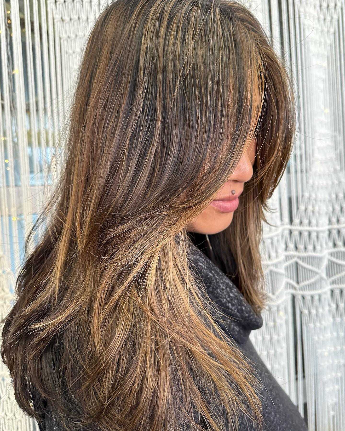 Woman showcasing her long, hand-painted highlighted hair.