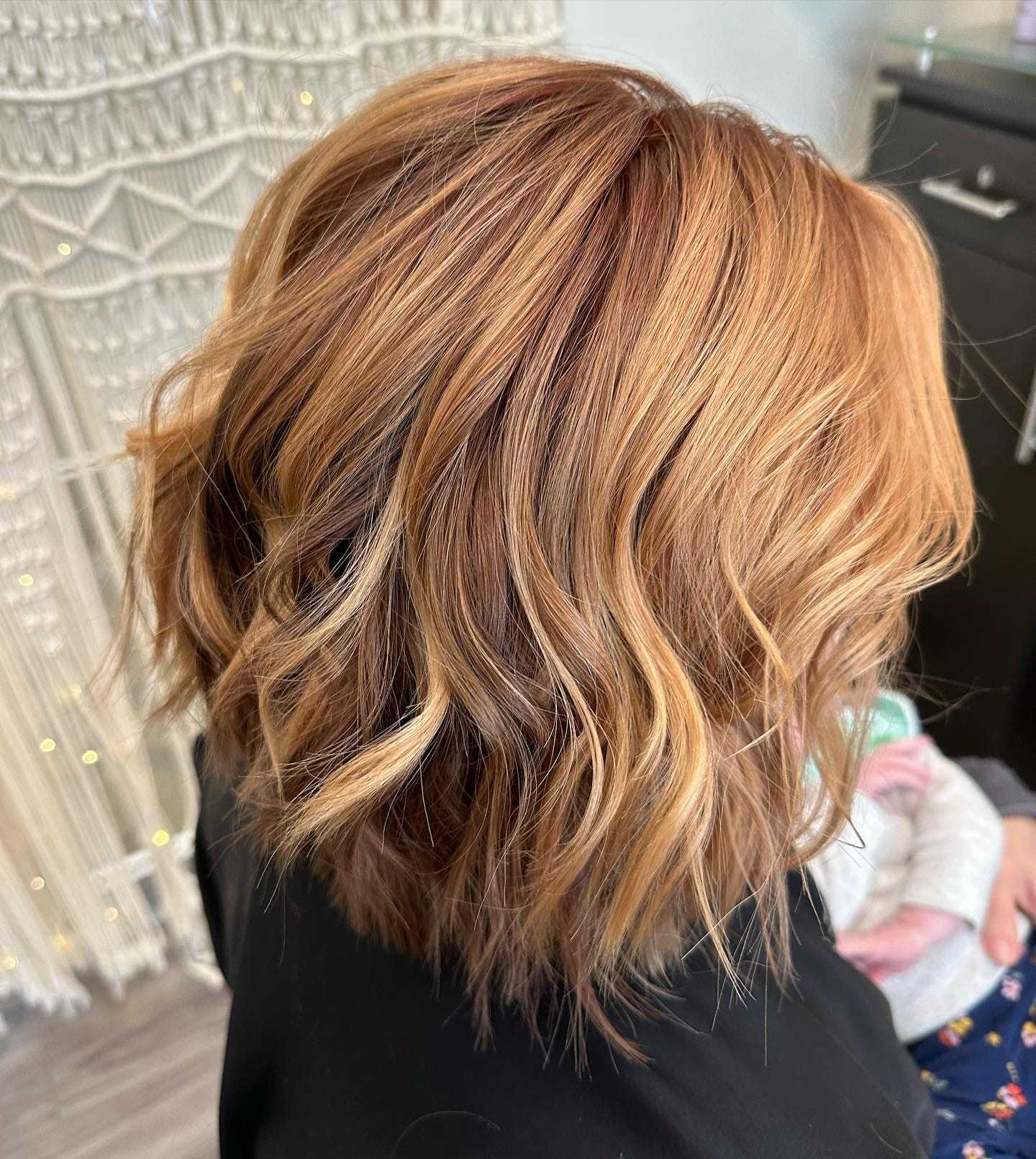 Woman showcasing her layered caramel balayage hairstyle.