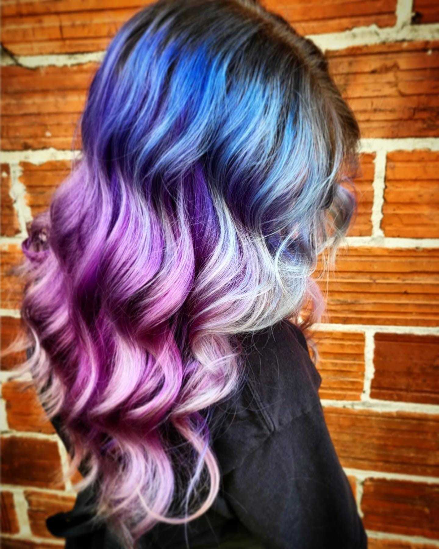 Woman with blue and purple ombré hair against a brick wall.